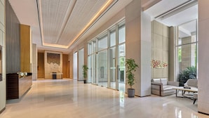 A spacious lobby with a polished floor, large windows, and a seating area with a sofa and armchairs. - Aravali Marriott Resort & Spa, Delhi NCR (Faridabad)