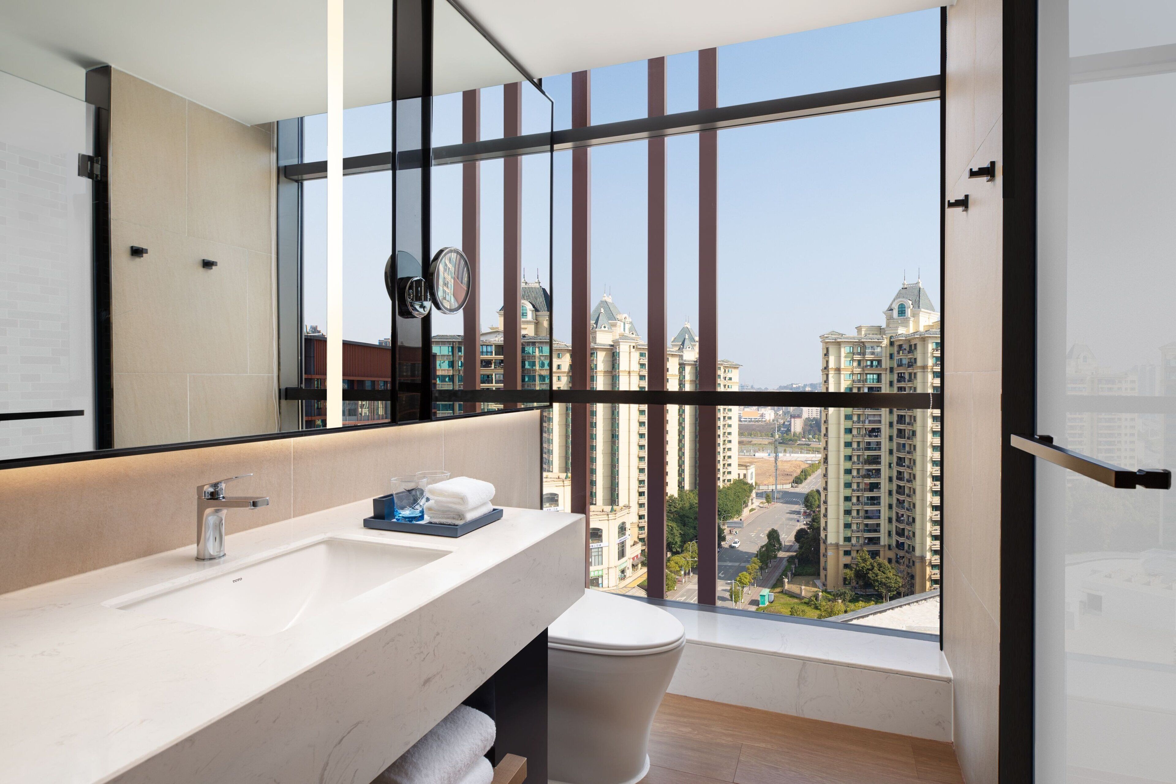 Un baño moderno con un ventanal grande, un lavamanos y un inodoro.