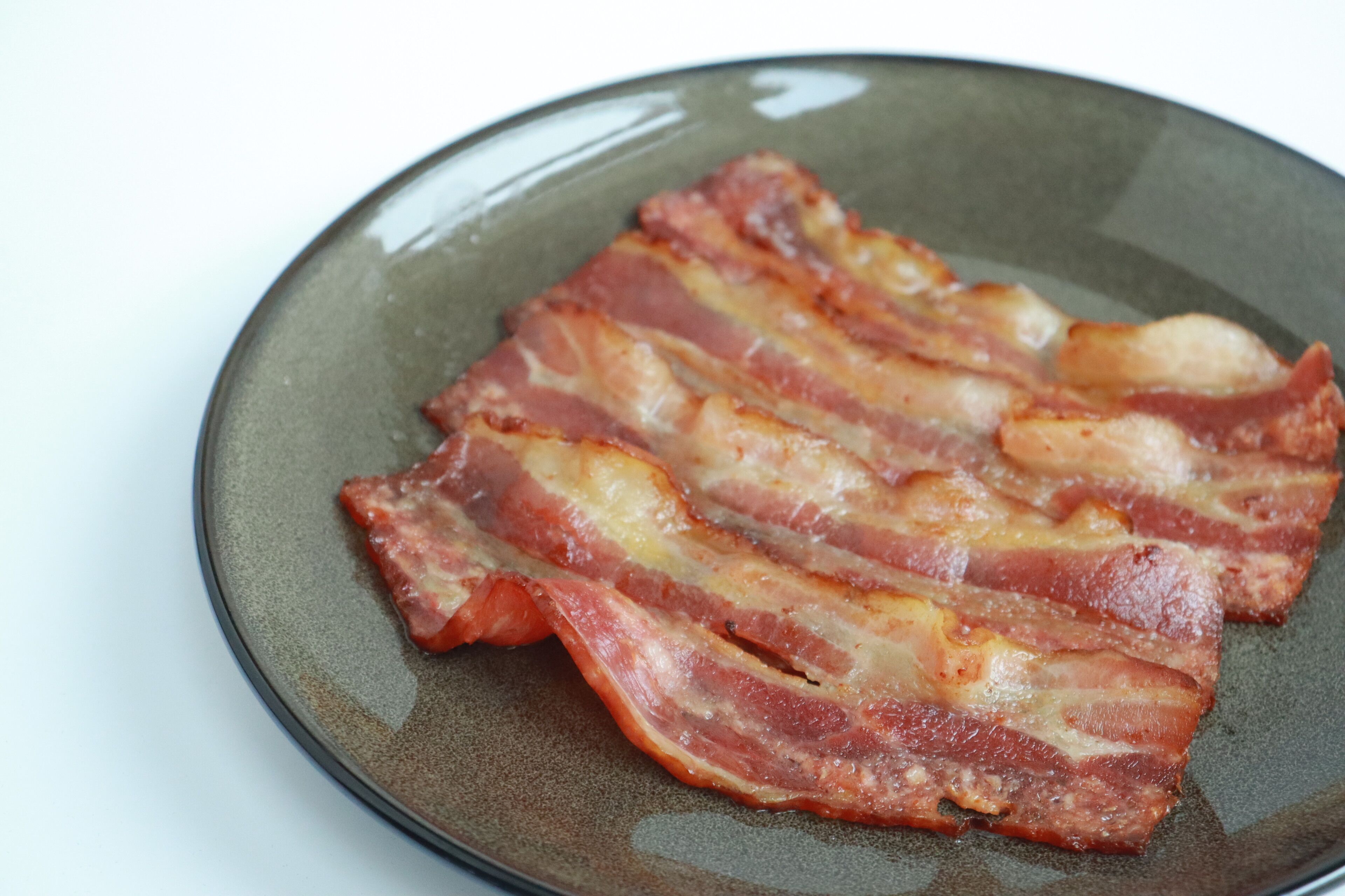 Un plato con varias tiras de tocino cocido.