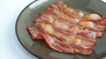 Un plato con varias tiras de tocino cocido.
