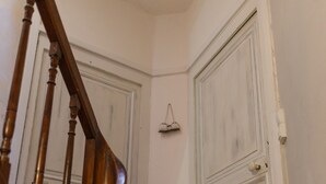 Una scala in legno che conduce a una porta bianca, con un piccolo oggetto appeso al muro.