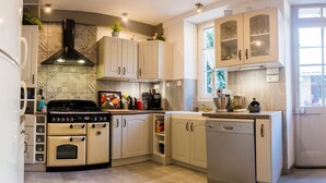 Una cucina compatta con piano cottura, forno, lavastoviglie e macchina da caffè.