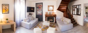 A living room with two sofas, a coffee table, a TV, a bookshelf, and a fireplace.