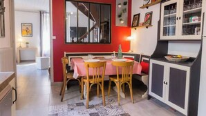 Zona pranzo con parete rossa, una scala e cucina con pensili.