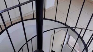 A spiral staircase with a black metal railing and a textured black floor. - Airy studio apartment in Copacabana, 4 blocks from the beach. (Rio de Janeiro)