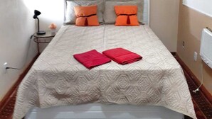 A small, neatly arranged bedroom with a bed, pillows, a bedside table, and a wall-mounted artwork. - Airy studio apartment in Copacabana, 4 blocks from the beach. (Rio de Janeiro)