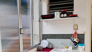 A compact kitchen with a dining table, chairs, a sink, and a window with blinds. - Airy studio apartment in Copacabana, 4 blocks from the beach. (Rio de Janeiro)