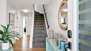 A staircase leading to a second floor, a potted plant, a patterned bench, and a mirror on the wall. - Compass Pointe Condominium - Steps to downtown, close to Lake Michigan (Grand Haven)