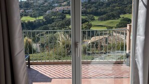 A room with a large window offering a view of a hillside with houses and greenery. - 🏖️ Villa - Swimming pool - 6 people - Near beaches & golf - Wifi (Sainte-Maxime)