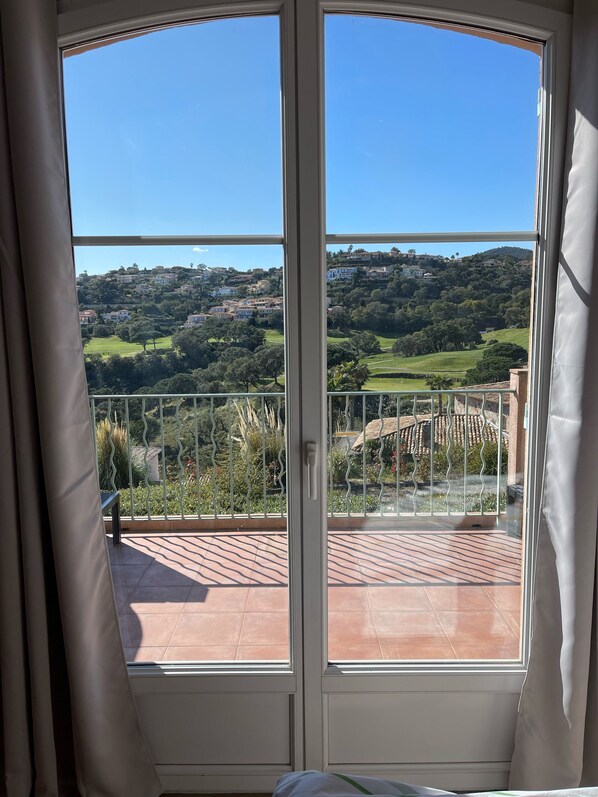 A room with a large window offering a view of a hillside with houses and greenery. - 🏖️ Villa - Pool - Sleeps 6 - Near Beaches & Golf - Wi-Fi (Sainte-Maxime)
