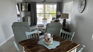 Un comedor con una mesa de madera, cuatro sillas, un frasco decorativo y vistas al balcón exterior.