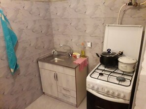 A compact kitchen with a sink, cabinets, and a stove.
