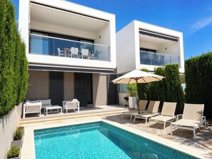 A modern two-story residential building with a swimming pool, outdoor seating, and a well-maintained garden. - Casa Descansa—a vacation to feel good, enjoy yourself, and relax! (Cala Mendia)