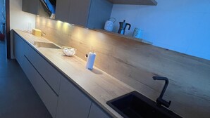 Una cocina moderna con encimera de madera, un lavamanos empotrado y un estante pequeño sobre la encimera.