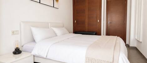 A bedroom with a bed, a nightstand, a wardrobe, and a painting on the wall.