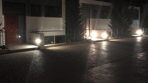 A modern building with a well-lit entrance and a paved driveway. - Casa Descansa - vacation to feel good, enjoy and relax! (Cala Mendia)