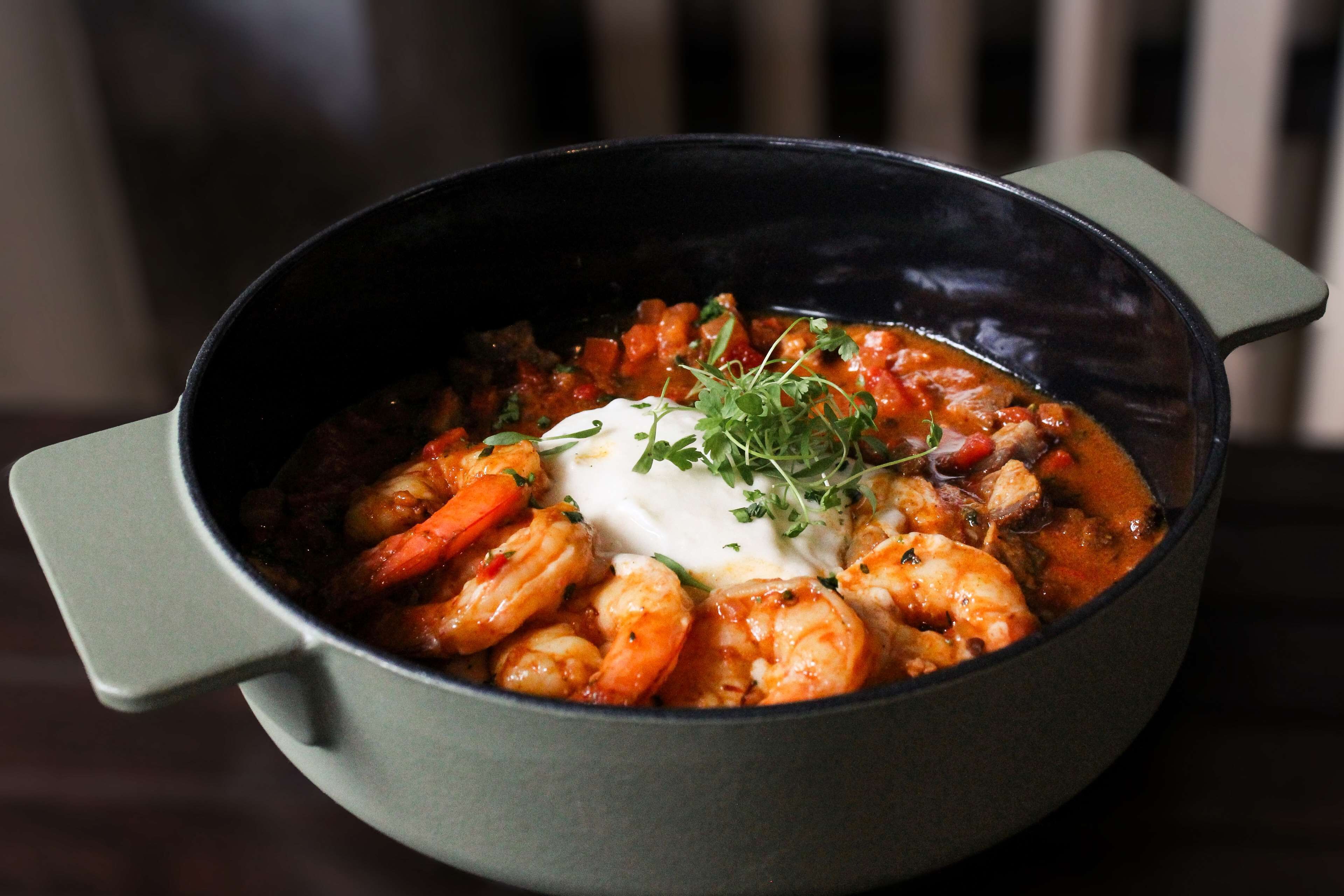 A bowl of shrimp stew with a dollop of sour cream and garnish.