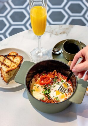 A breakfast setting with a bowl of eggs, toast, and a glass of orange juice on a table. - Hyatt Centric Congress Ave Austin (Austin)