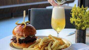 Et måltid bestående af en burger, pommes frites og et glas hvidvin på et bord.