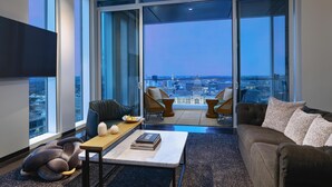A modern living room with a sofa, armchairs, a coffee table, and a view of the city through large windows. - Hyatt Centric Congress Ave Austin (Austin)