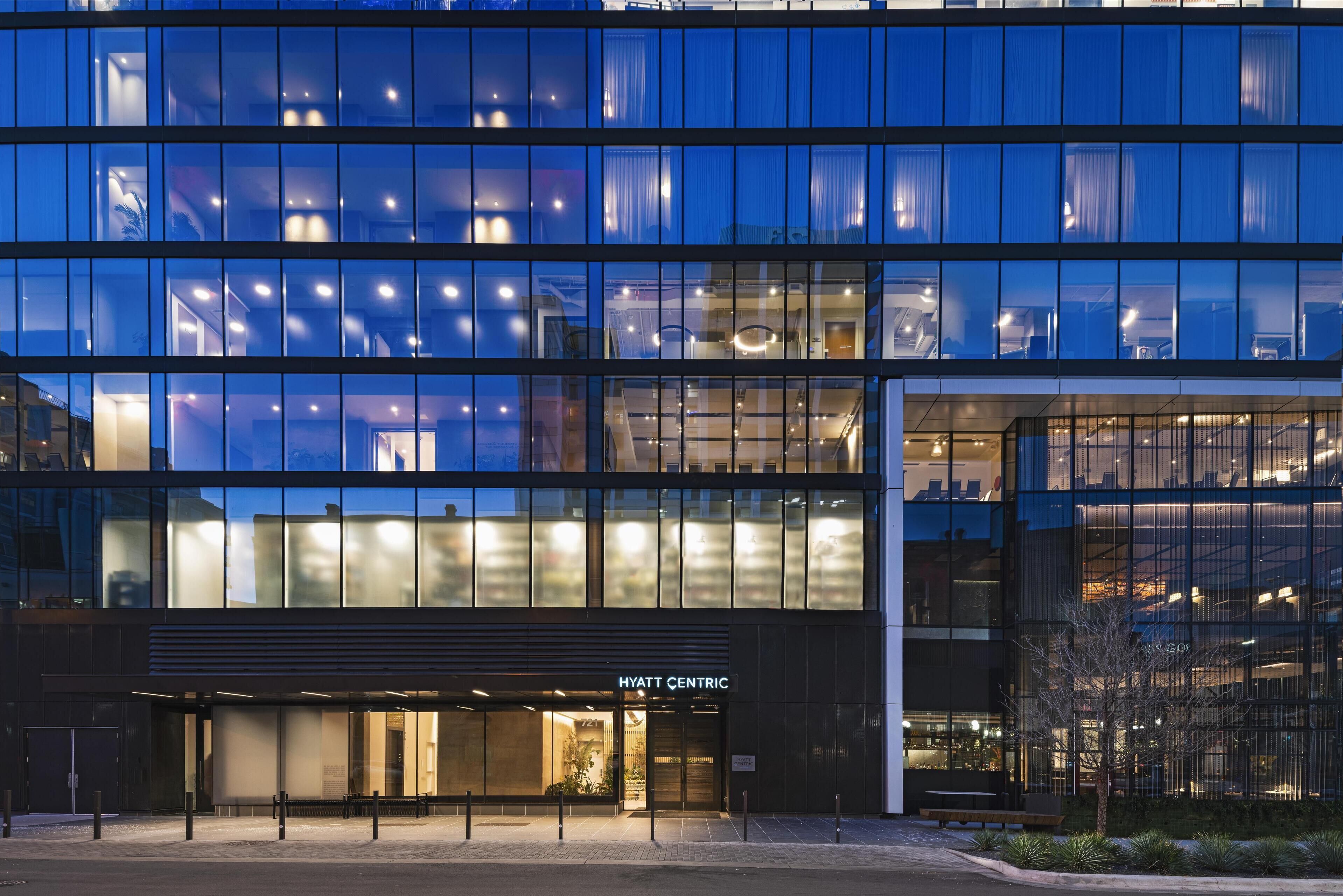 Un hôtel moderne avec une façade en verre, une entrée bien visible et une enseigne indiquant « HYATT CENTRIC ».