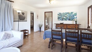 A living room with a sofa, a dining table with chairs, a painting, and a potted plant. - Ideal for families with pool, Can Seguinot (Pollensa / Pollença)