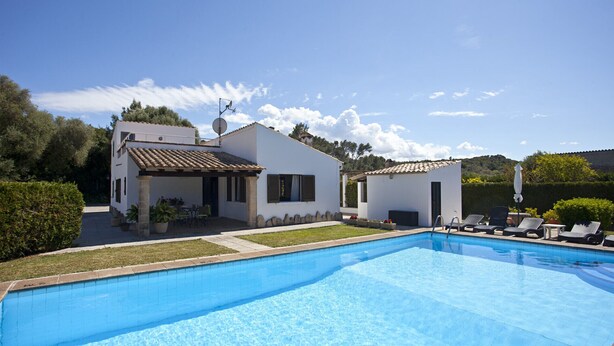 A poolside area with a clear blue pool, a white building with a tiled roof, and a smaller structure with a white wall and a tiled roof. - Ideal for families with pool, Can Seguinot (Pollensa / Pollença)