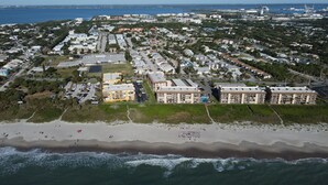 An aerial view of a coastal residential area with beachfront properties, a marina, and a large hotel complex. - Coastal Getaway - Steps from the Beach! (Cape Canaveral)