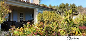 Una casa tradicional de estilo mediterráneo con tejado de baldosas, un balcón y un jardín con diversas plantas.