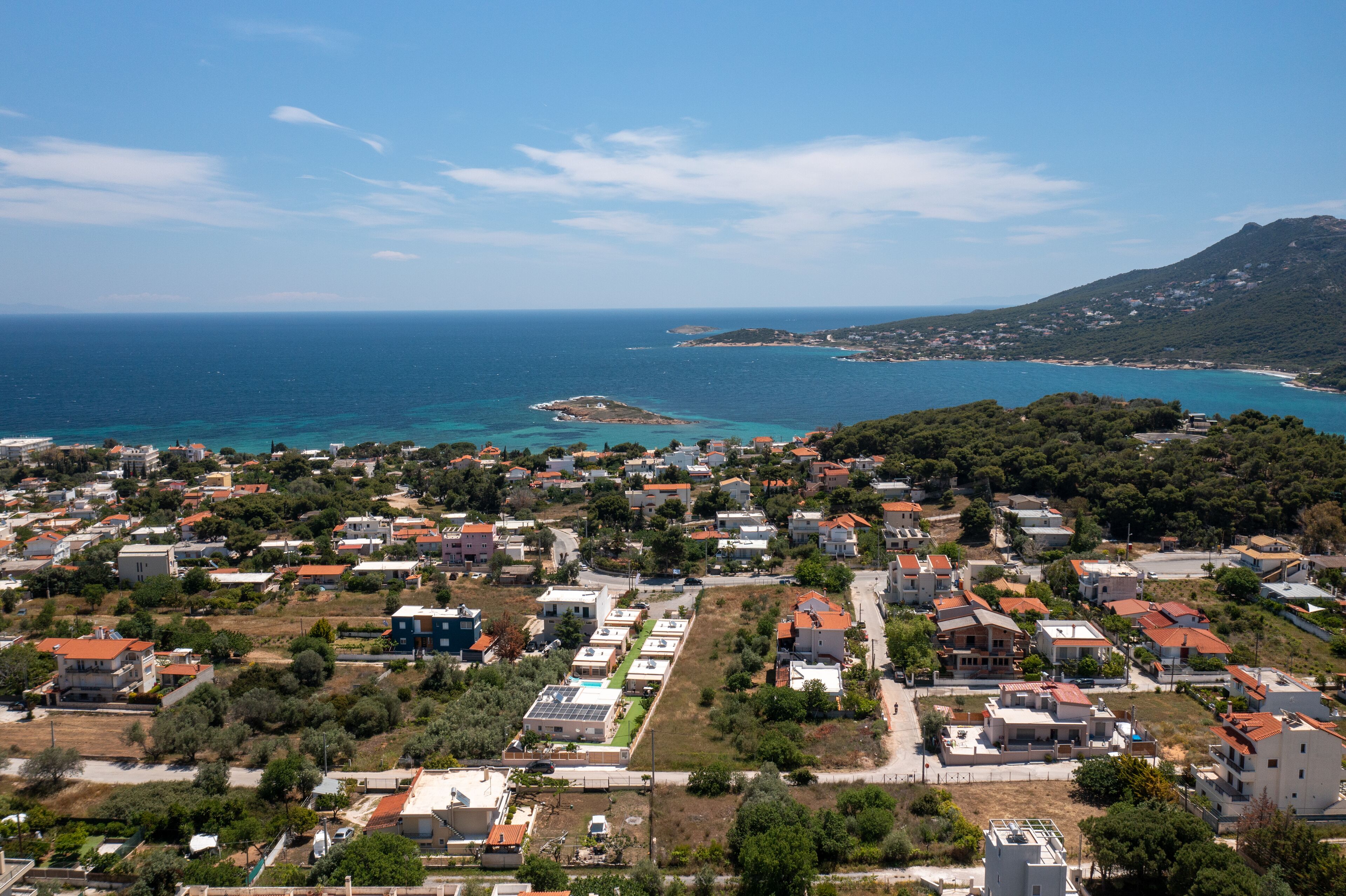 Un pueblo costero con edificios residenciales, una playa y una montaña al fondo.