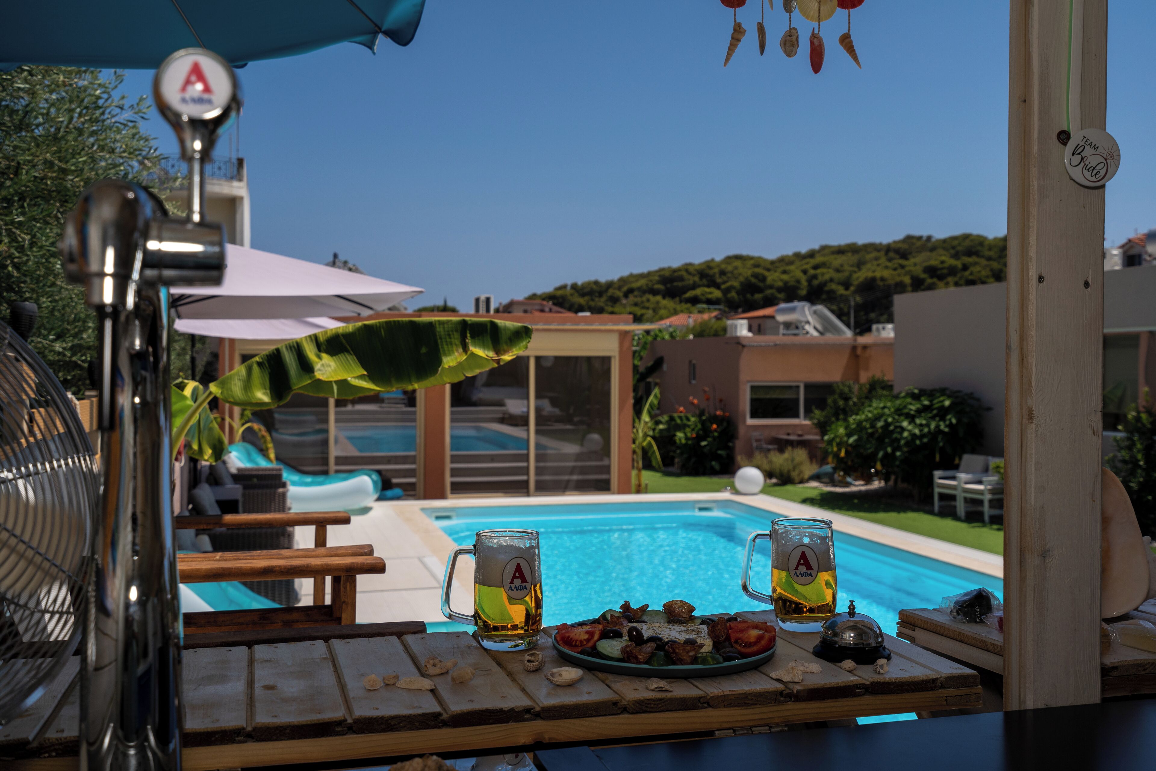 Eine Poolbar mit Holztisch, zwei Biergläsern und einem Teller Essen.
