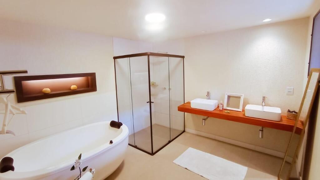 Un baño moderno con ducha envuelta en vidrio, una bañera independiente y un tocador con espejo.