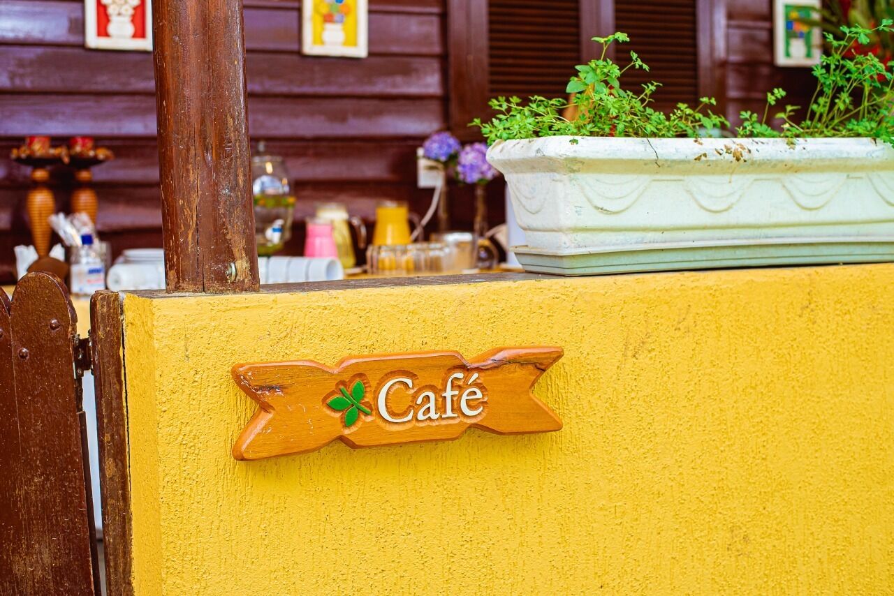 A wooden sign with the word "Café" and a clover symbol, indicating a café location.