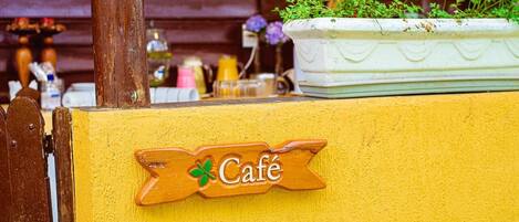 A wooden sign with the word "Café" and a clover symbol, indicating a café location.