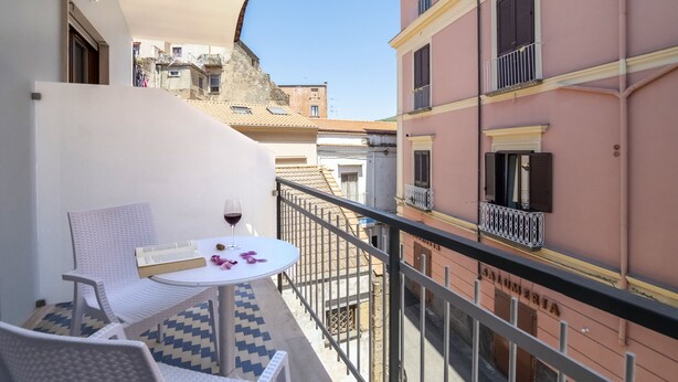 A balcony with a table, chairs, and a bottle of wine. - Neva-Elegant Suite with Balcony in Massa Lubrense center 10 minutes from Sorrento (Massa Lubrense)