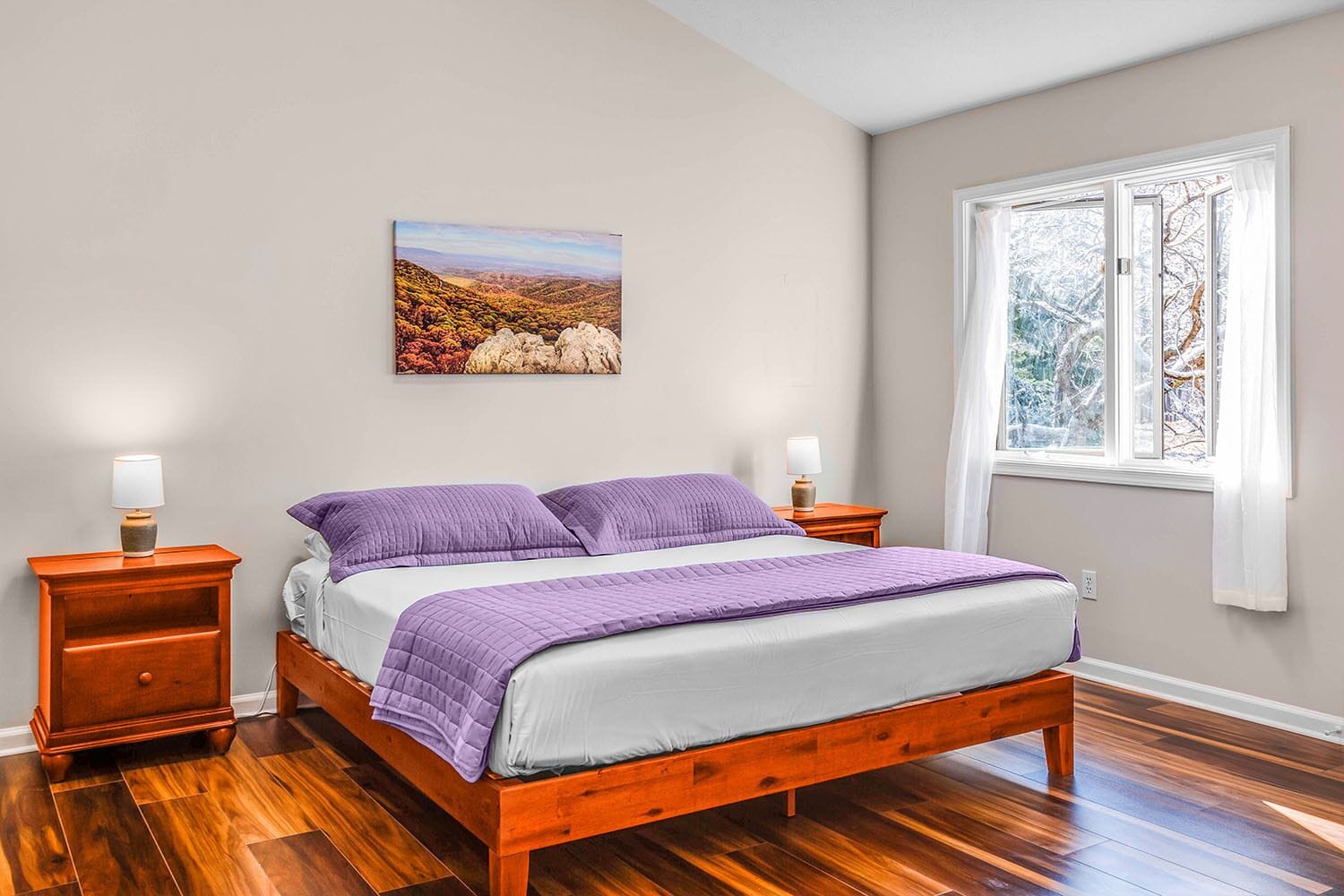 Une chambre à coucher avec un lit en bois, deux tables de chevet, une fenêtre avec des rideaux et un tableau au mur.