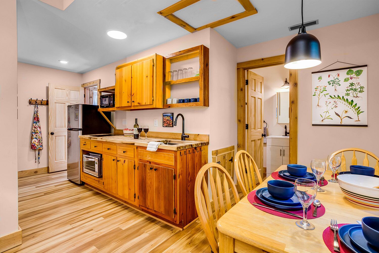 A compact kitchen with wooden cabinets, a built-in oven, and a dining area with a table set for two.