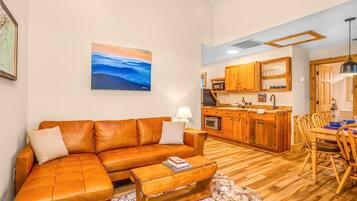 Un salón acogedor con un sofá de cuero, una mesa de centro de madera y un cuadro en la pared.