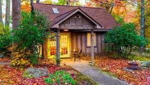 A rustic cabin with a wooden exterior, a front porch, and a small table with chairs.