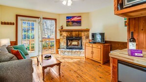 A cozy living room with a stone fireplace, wooden furniture, and a television.