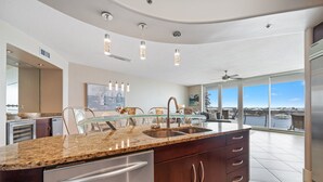 A modern kitchen with granite countertops, stainless steel appliances, and a large island with a glass-top table.