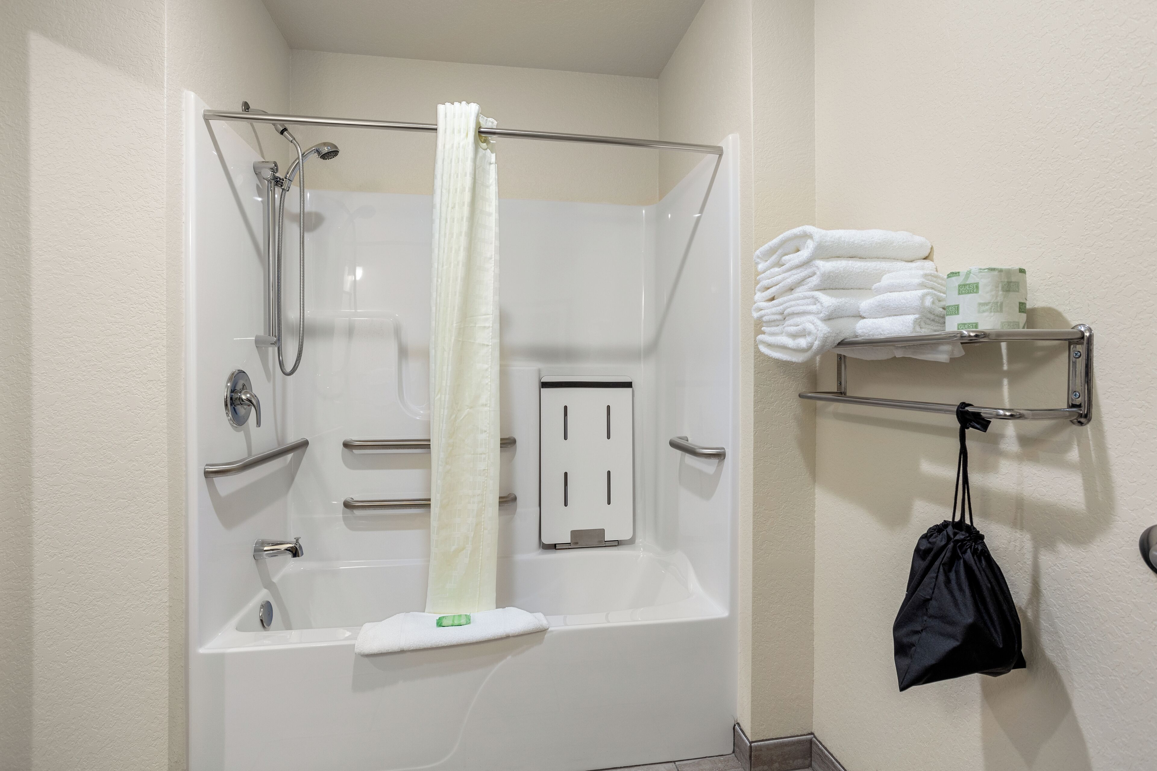 A bathroom with a shower, a bathtub, and a towel rack with towels and toiletries.