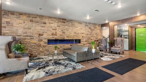 Un vestíbulo moderno con pared de piedra, chimenea, sofás de cuero y una puerta verde.
