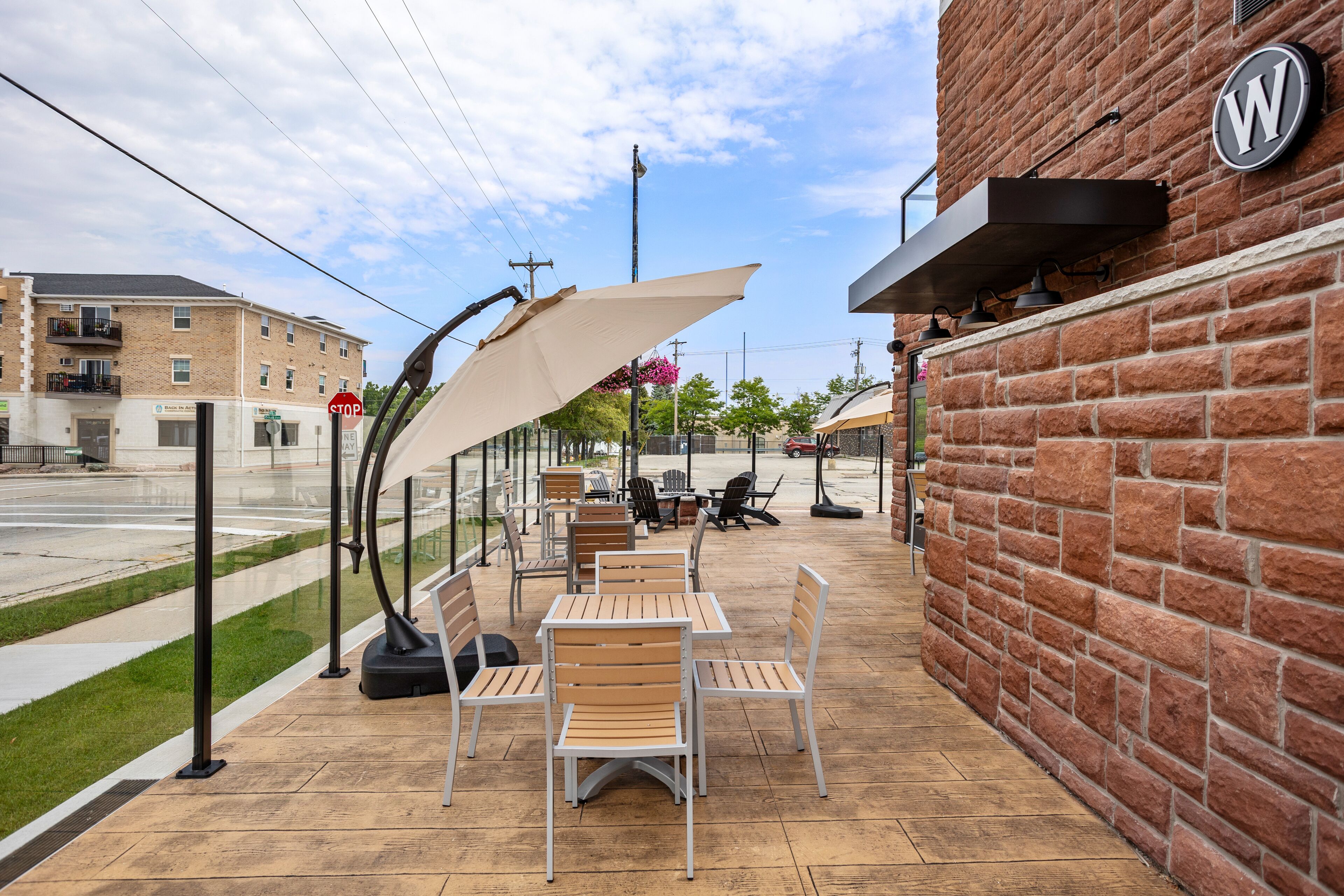 An outdoor patio with tables and chairs, a brick wall, and a stop sign in the background.