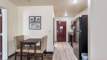 Una cocina compacta con comedor, que incluye una mesa y sillas, un refrigerador y una puerta con un cartel.