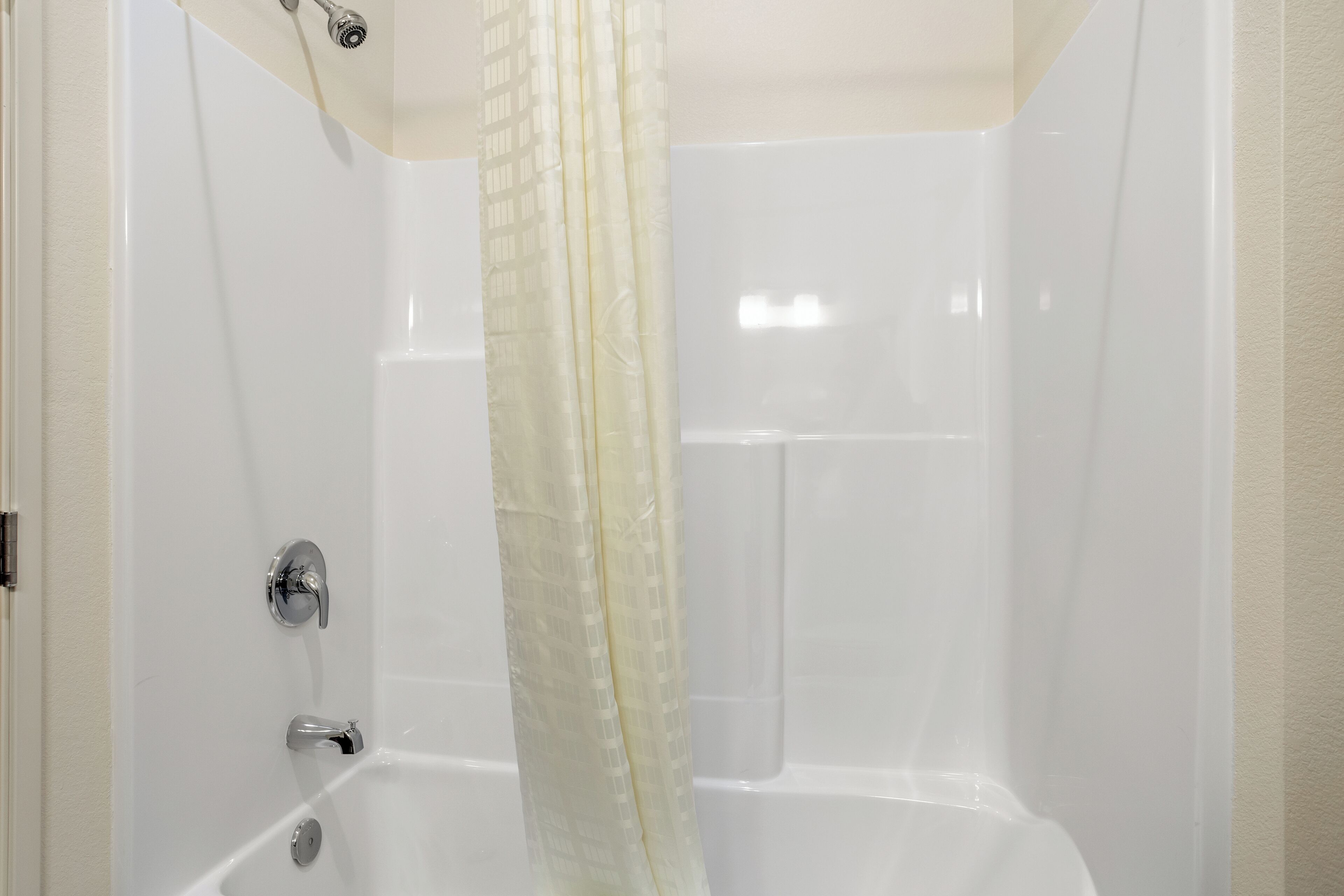 A white bathtub with a showerhead and a curtain.