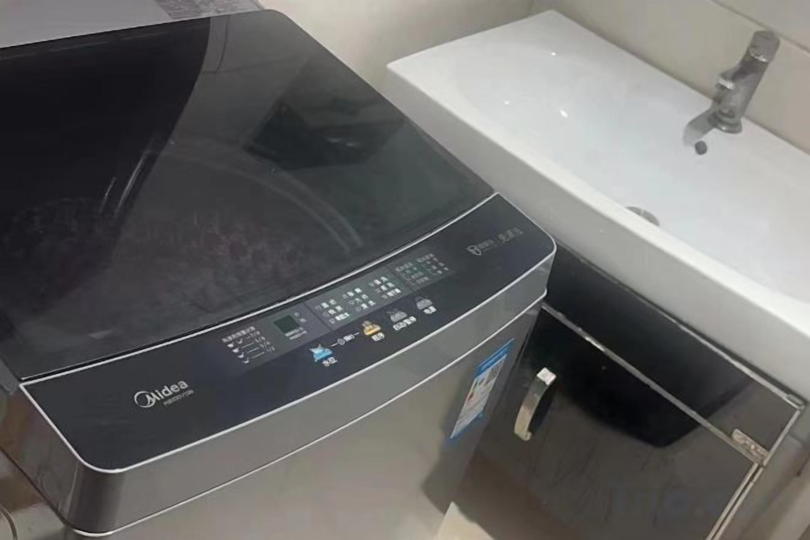 A black appliance with a digital display, a sink, and a faucet in a bathroom.