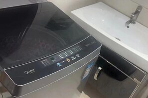 A black appliance with a digital display, a sink, and a faucet in a bathroom. - Yizhang Yiyuan Hotel (Yizhang)