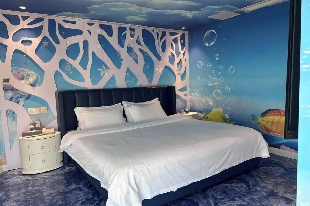 Un dormitorio con cama, mesita de noche y un mural en la pared.