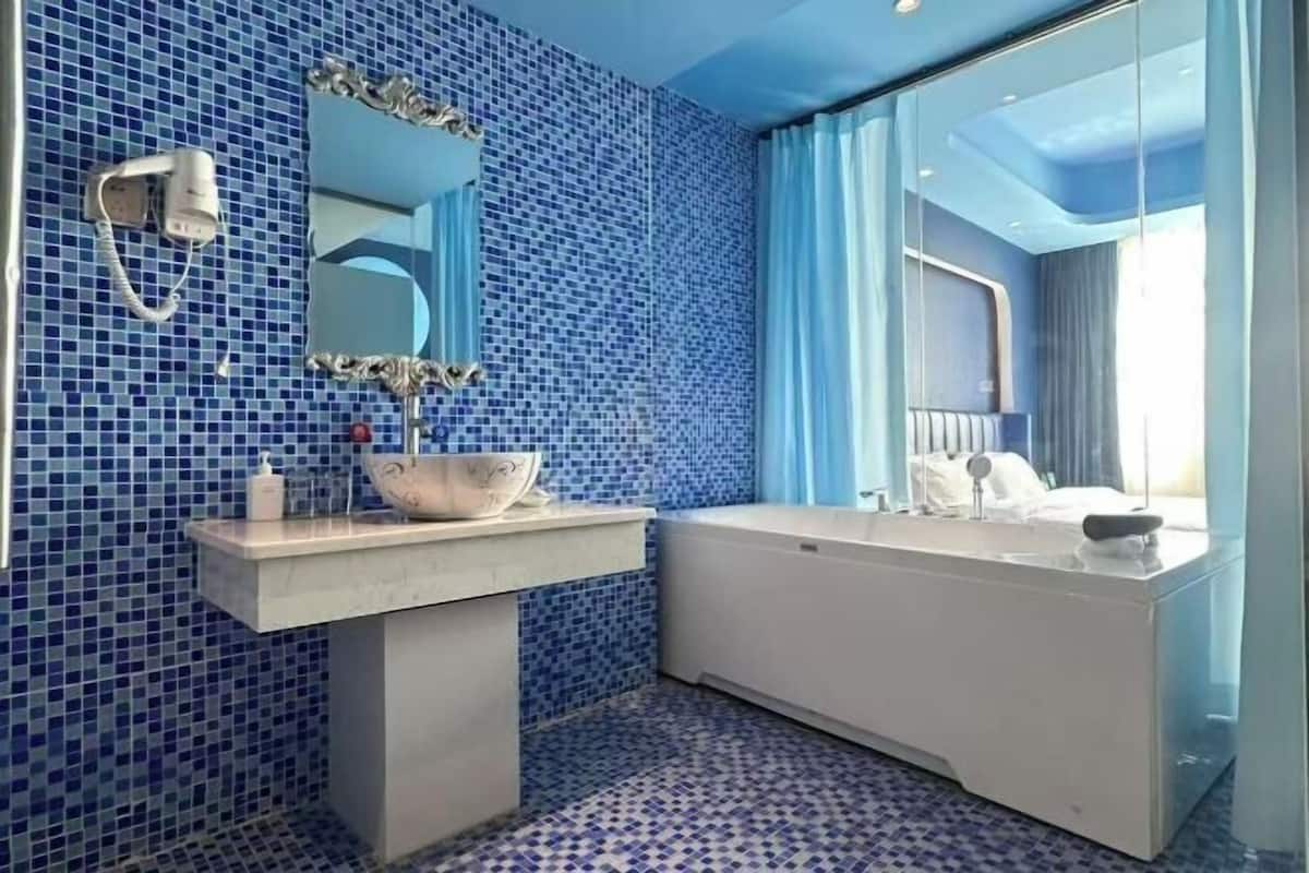 Un baño con mosaicos azules, un lavamanos blanco, una bañera y un espejo grande.